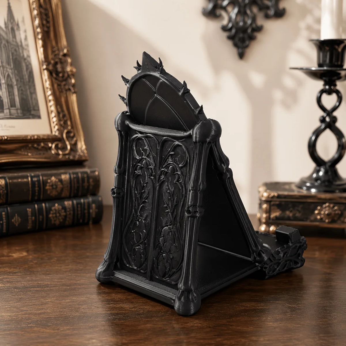 A black gothic skull phone stand with intricate detailing sits on a dark wooden surface.