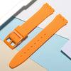 An orange soft silicone watch strap is shown next to its replacement tools on a light background.