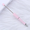 A pink DIY beadable pen with a silver tip is shown resting on a white, fluffy surface.