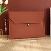 A brown leather document organizer bag with a flap closure shown next to a white tulip.