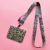 A leopard print ID holder attached to a black lanyard on a pink background.