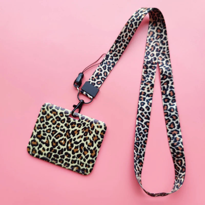 A leopard print ID holder attached to a black lanyard on a pink background.