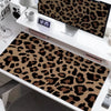 A large leopard print desk pad is displayed on a white desk next to a monitor and a clock.