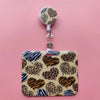 A leopard print card holder clip with a round holder and a rectangular case on a pink background.