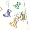 Three colorful paper clip shapes of sitting dogs in green, purple, and gold on a white background.