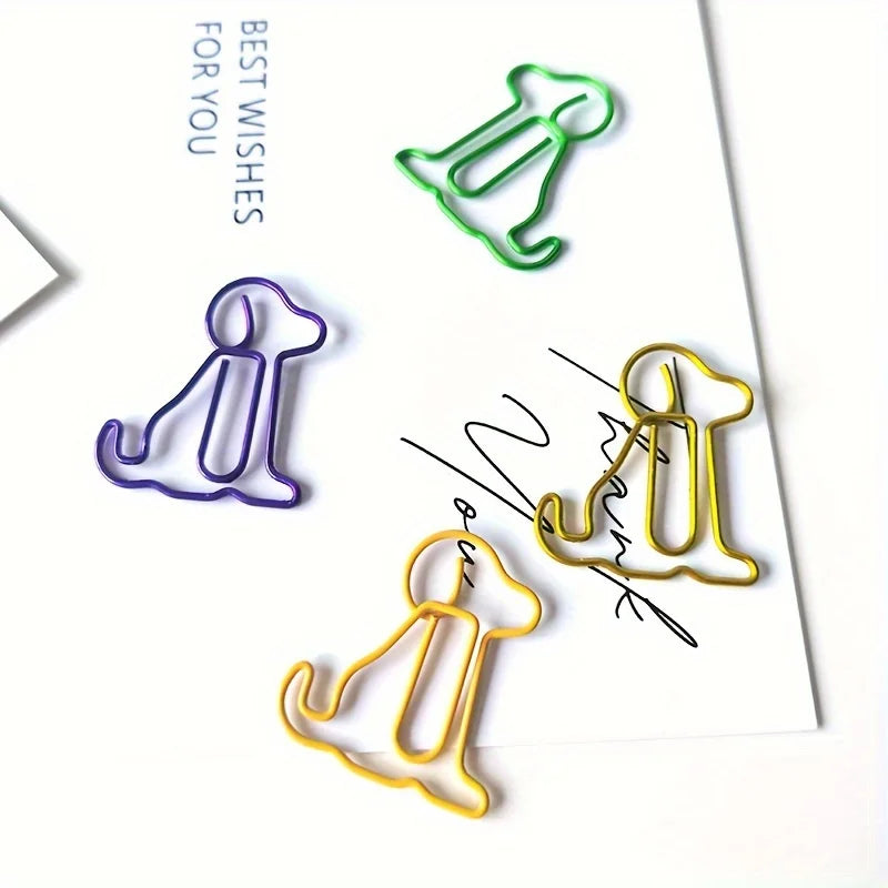 Three colorful paper clip shapes of sitting dogs in green, purple, and gold on a white background.