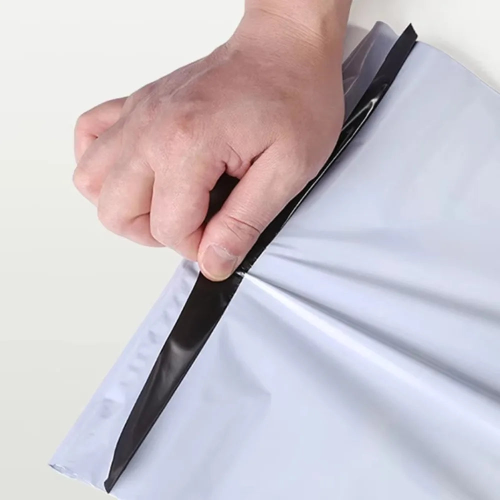A hand is sealing a white dustproof mailing bag with a black sealing strip.