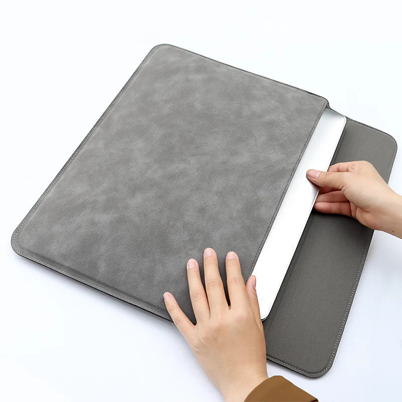 Eine Hand legt eine graue PU-Leder-Laptophülle über einen weißen Laptop.