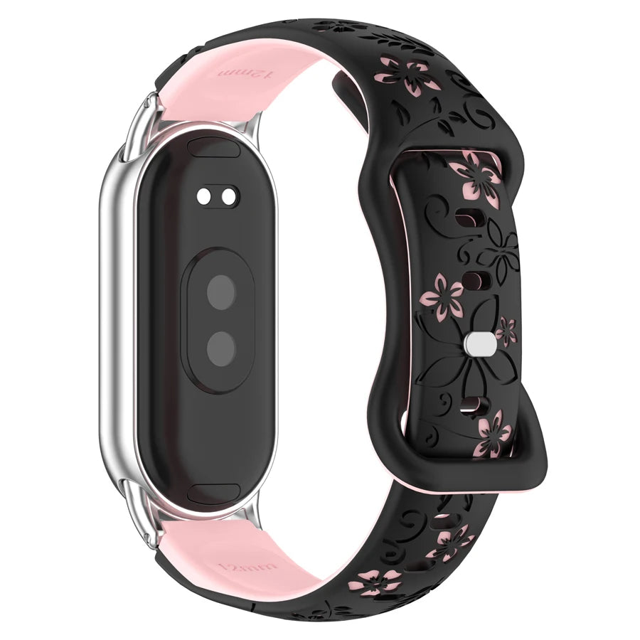 A black silicone watch band with pink floral engravings and a silver casing for a smart band.