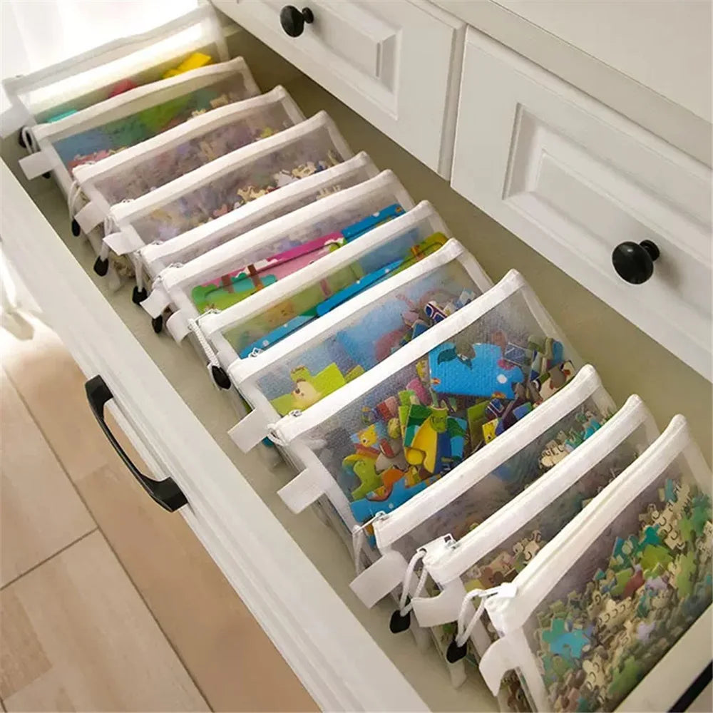 A set of reusable zipper mesh storage bags filled with colorful fabric and toys, stored in a white cabinet drawer.