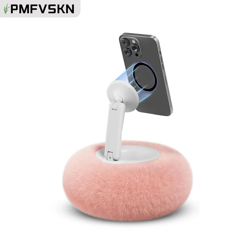 A magnetic pillow stand holding a smartphone, featuring a pink fuzzy base and a white stand.