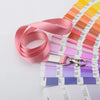 Una pila de soportes resistentes para credenciales de color rosa y morado con cordones y llaveros adjuntos.
