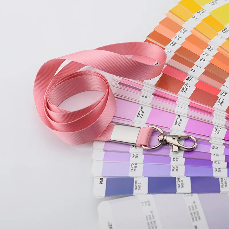 Una pila de soportes resistentes para credenciales de color rosa y morado con cordones y llaveros adjuntos.