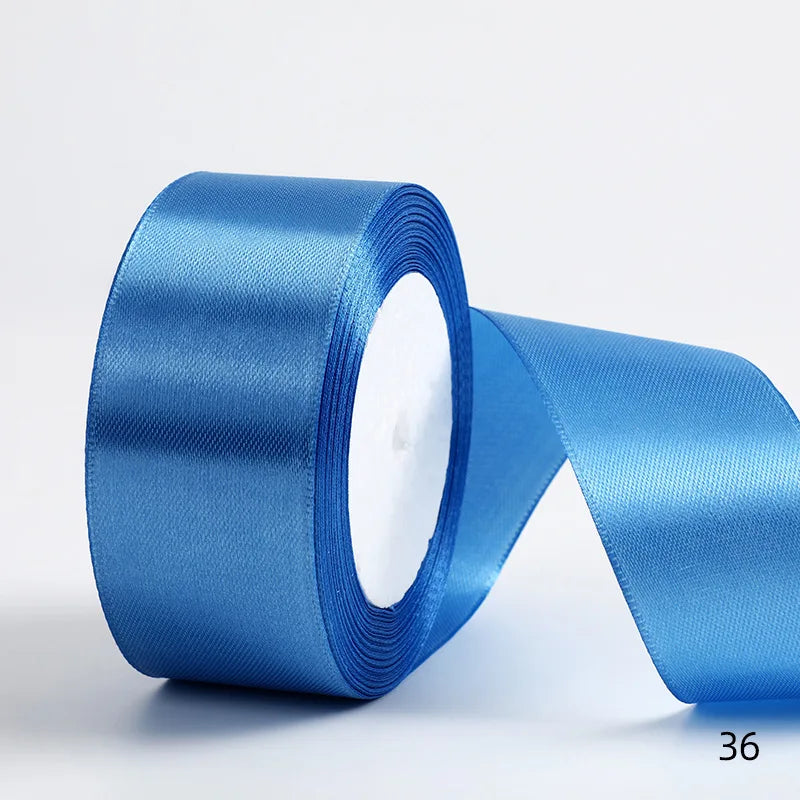 A roll of bright blue satin ribbon lying next to a loose strip.