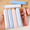 A collection of gradient double-sided tape pens in various shades of pink and blue are displayed on a wooden surface.