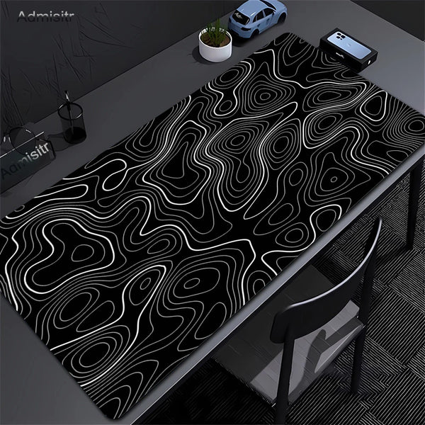 Extra large abstract desk mat with black and white topographic lines on a dark surface.