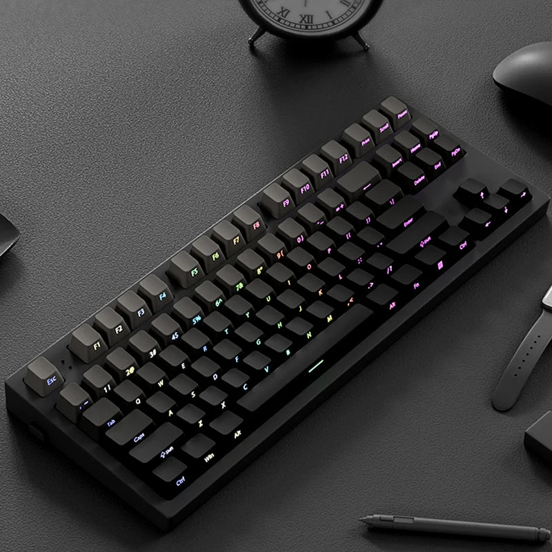 A close-up view of a black mechanical keyboard with purple keycaps and side printing on a dark surface.