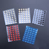 A collection of adhesive glide feet in various colors, including white, silver, and blue, arranged in small plastic sheets.