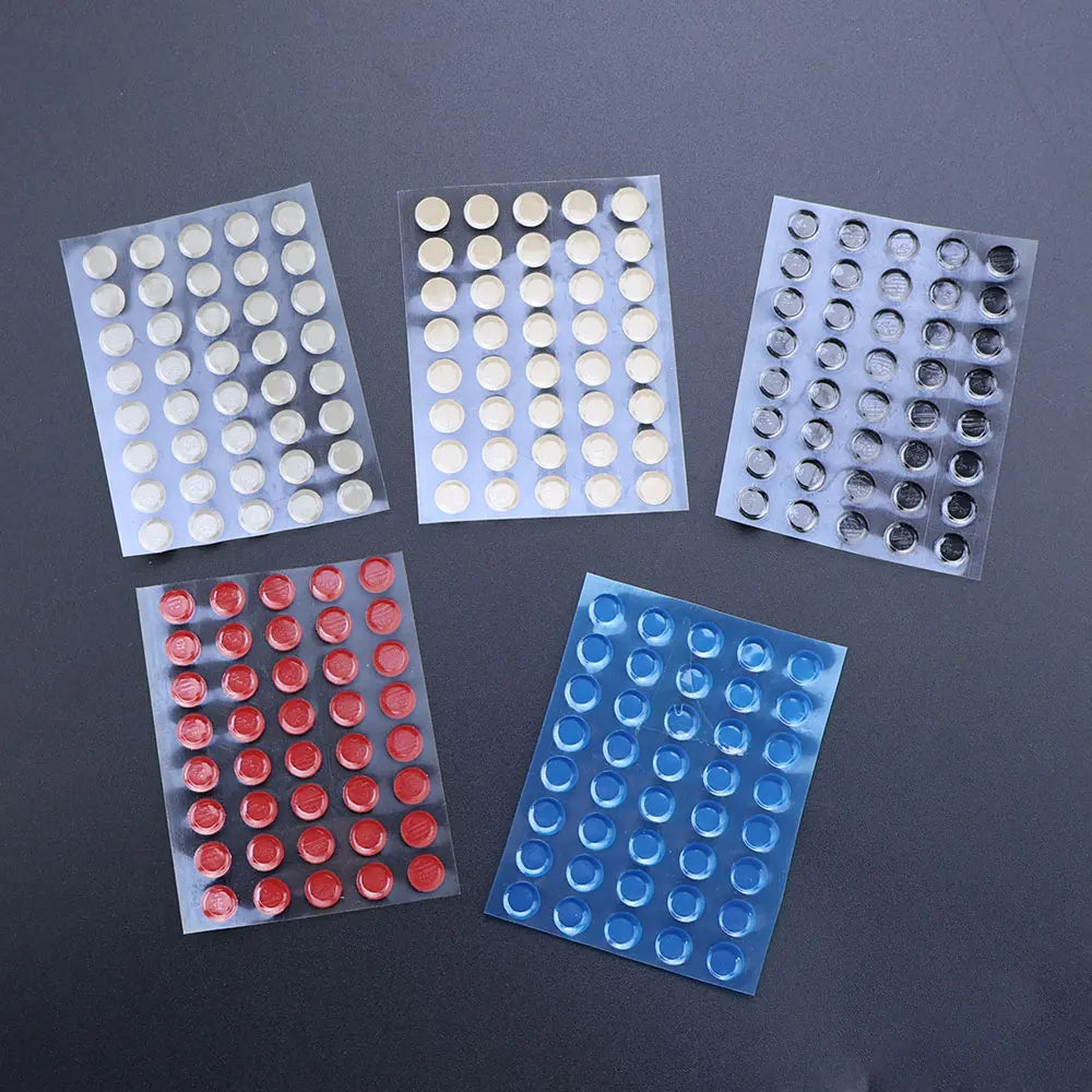 A collection of adhesive glide feet in various colors, including white, silver, and blue, arranged in small plastic sheets.