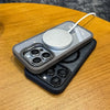 A gray magnetic shockproof phone case for an iPhone is shown resting on a wooden surface.