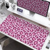 A large leopard print desk pad featuring pink and purple spots is displayed on a white desk.