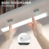Hands hold a white body sensor lamp light strip illuminating a surface, showing the charging interface.