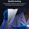 A hand in a blue glove is inspecting a clear protective film on an iPad screen under bright light.