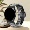 A black smartwatch is shown on a gray patterned nylon watch strap, resting on a light surface.