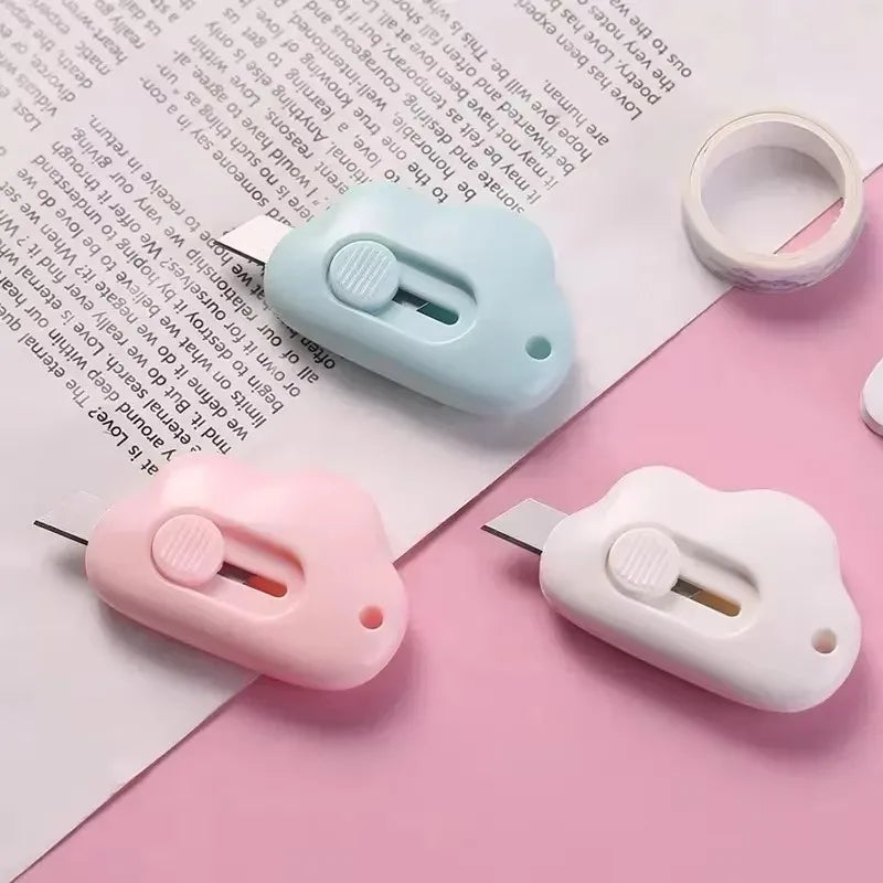 A set of multi-color rabbit cloud utility knives, including a light blue and pink knife, resting on a white paper.