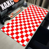 A red and white checkered desk mat is placed on a gray desk next to a keyboard and gaming controller.