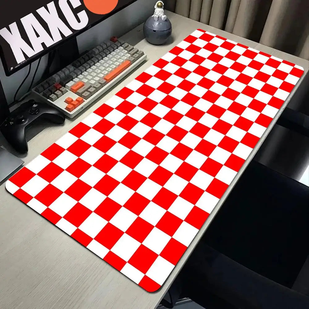 A red and white checkered desk mat is placed on a gray desk next to a keyboard and gaming controller.
