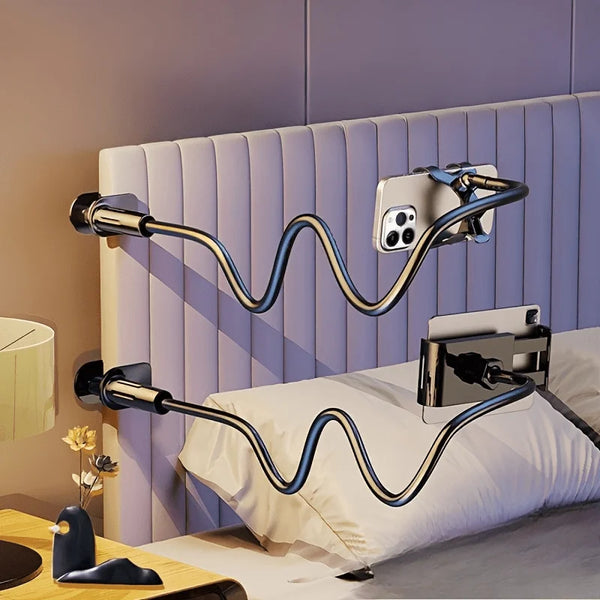 A silver adjustable phone and tablet stand is shown mounted on a headboard, with a white pillow nearby.