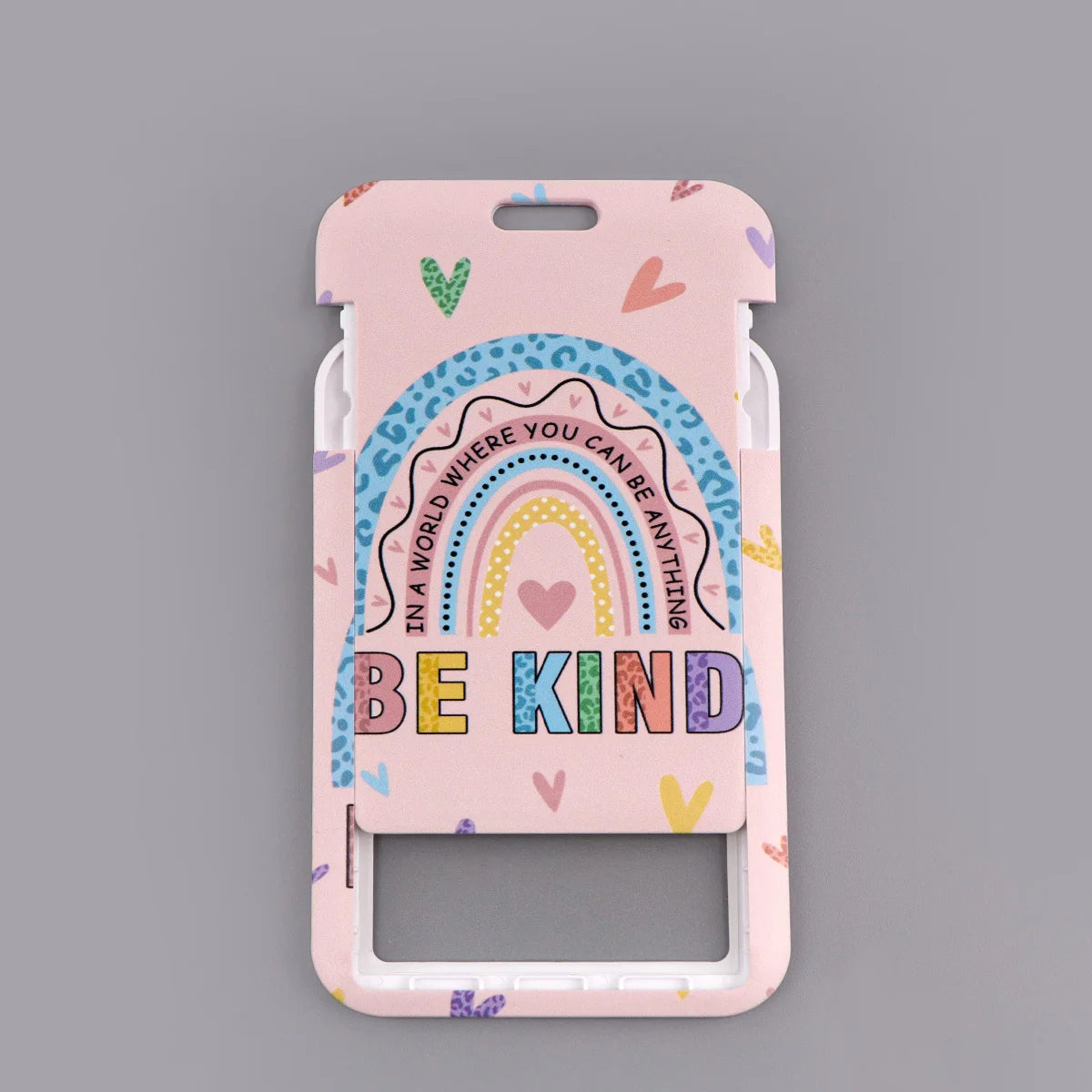 A pink ID badge holder featuring a rainbow design and the text BE KIND