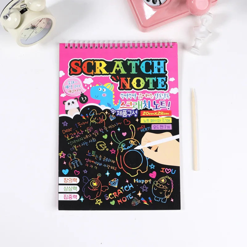 A pink spiral notebook titled Scratch Note with colorful drawings and text, next to a pink cosmetic item.