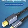A close-up view of a silver USB-C to USB-B printer cable with a braided connector and gold plug against a blue background.