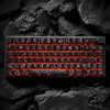 Nahaufnahme einer schwarzen mechanischen Tastatur mit roten Kohlenstoff-Keycaps auf einer dunklen, strukturierten Oberfläche.