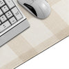 A silver computer mouse and a white keyboard are placed on a beige plaid pattern non-slip mouse pad.
