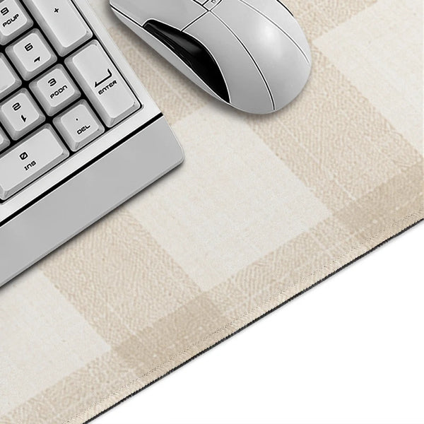 A silver computer mouse and a white keyboard are placed on a beige plaid pattern non-slip mouse pad.