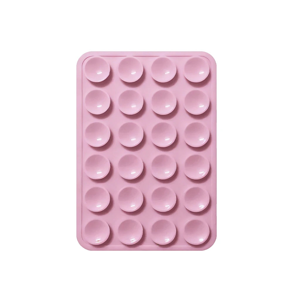 A pink reusable silicone suction phone mount with multiple circular holes for mounting devices.