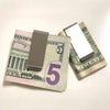 A stainless steel money clip resting on top of a five dollar bill.