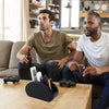 A man is sitting at a wooden table with a PU leather remote caddy organizer and a game controller.