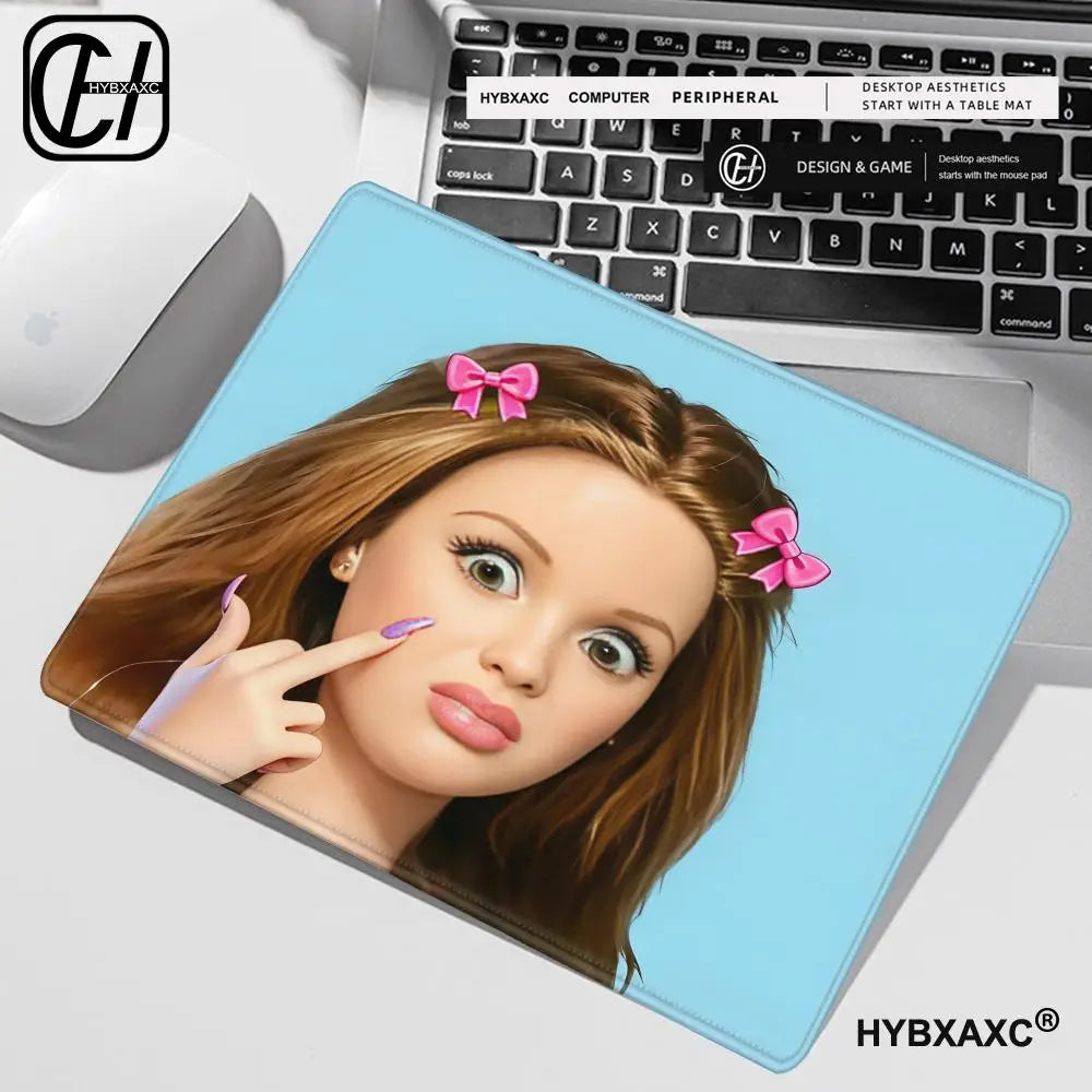 A mouse pad featuring a cute doll face with long brown hair and pink bows, placed next to a laptop.