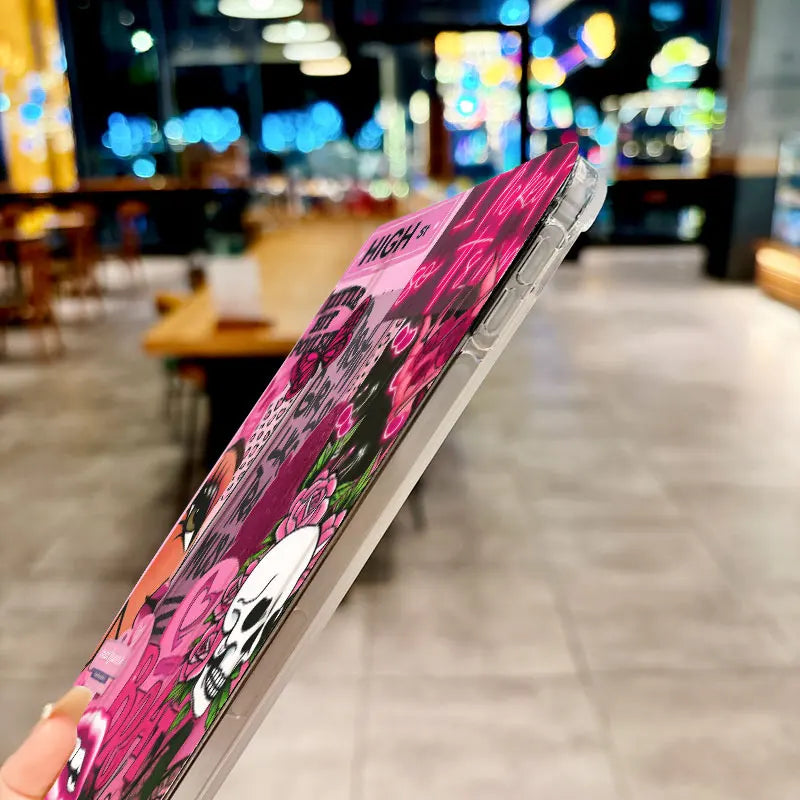 A pink and black anti-drop tablet case for an iPad is shown diagonally in a blurred indoor setting.