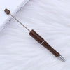 A brown DIY beadable pen with a silver tip rests on a white, fluffy surface next to a ruler.