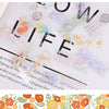 A sheet of decorative transparent washi tape featuring floral and nature-inspired designs on a white background.