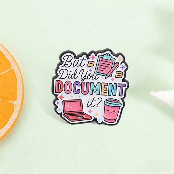 An enamel pin featuring the text But Did You Document It? surrounded by icons of a laptop and a document.