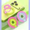 A pink and lime green magnetic ring grip with a foldable kickstand shown next to a yellow MagSafe phone.