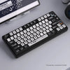 A close-up view of a black PBT transparent pudding style keycap set for a keyboard, with a smartphone in the background.