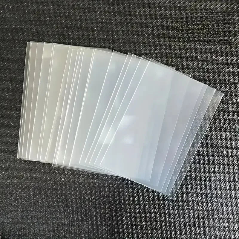 A fan of clear protective sleeves for trading cards, showing a stack of translucent plastic sleeves.