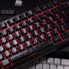Close-up of a black mechanical keyboard with carbon fiber keycaps and red backlit keys.